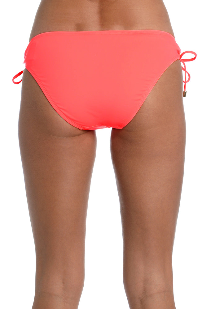 
            
                Load image into Gallery viewer, Model is wearing a hot coral colored side-tie hipster swimsuit bottom from our Best-Selling Island Goddess collection.
            
        