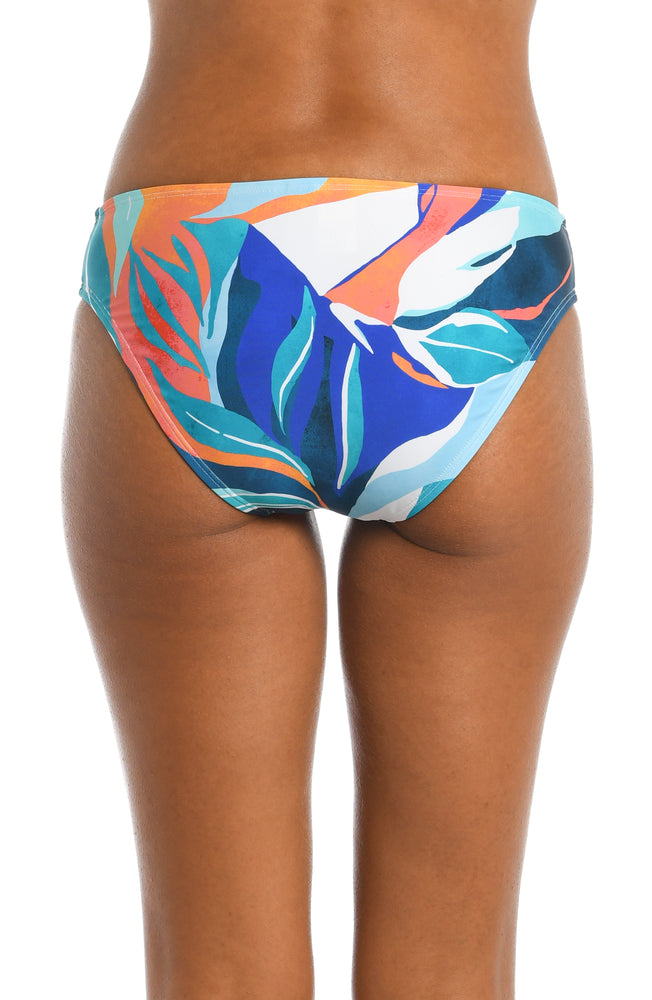
            
                Load image into Gallery viewer, Model is wearing a blue multi colored tropical printed hipster bottom from our Coastal Palms collection!
            
        