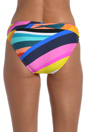 
            
                Load image into Gallery viewer, Model is wearing a striped bright multicolored shirred band hipster bikini bottom from our Sunscape collection.
            
        