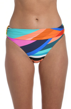 
            
                Load image into Gallery viewer, Model is wearing a striped bright multicolored shirred band hipster bikini bottom from our Sunscape collection.
            
        