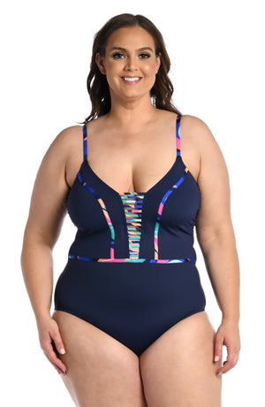 Model is wearing a bold paint-like stroke of vibrant dark colors printed on this plunge one piece from our Painted Leaves collection!