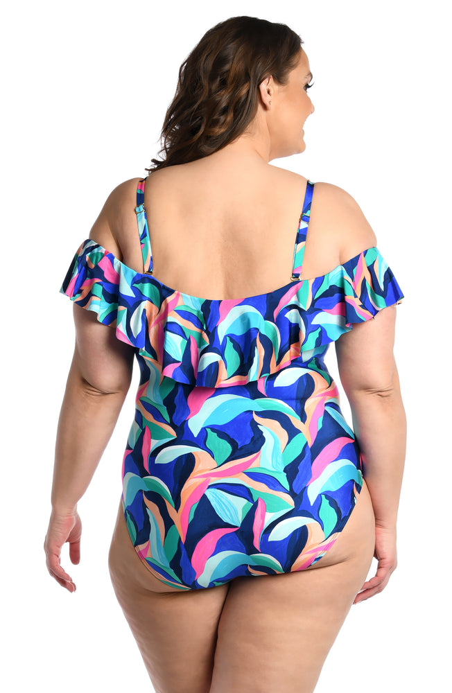 Model is wearing a bold paint-like stroke of vibrant dark colors printed on this off shoulder ruffle one piece from our Painted Leaves collection!