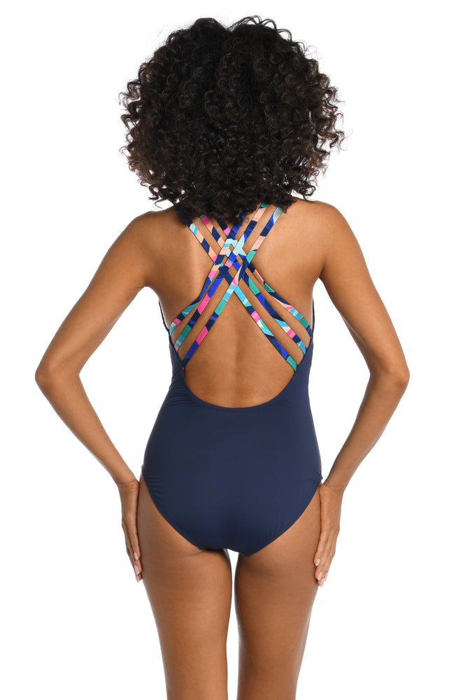 Model is wearing a bold paint-like stroke of vibrant dark colors printed on this multi-strap crossback one piece from our Painted Leaves collection!