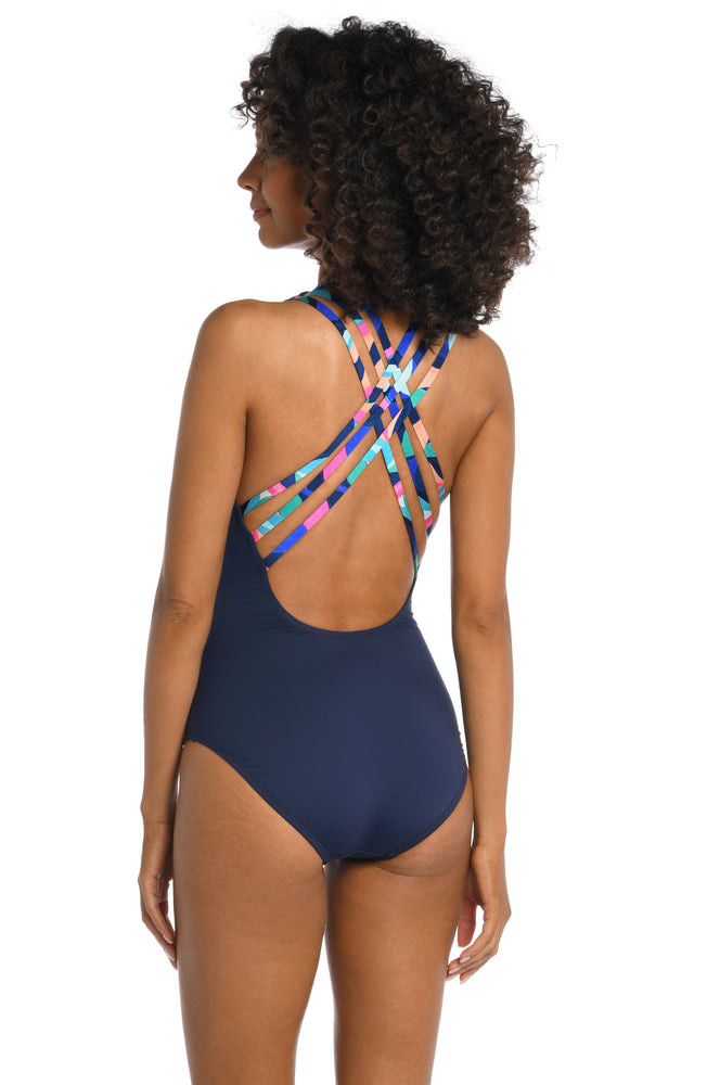 Model is wearing a bold paint-like stroke of vibrant dark colors printed on this multi-strap crossback one piece from our Painted Leaves collection!