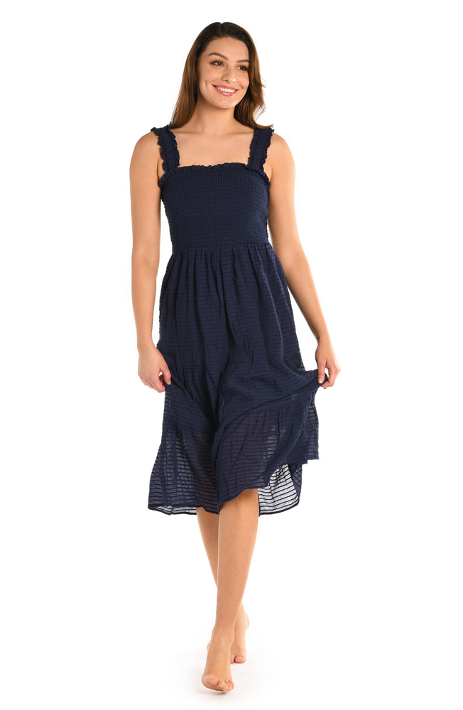 Model is wearing a solid indigo colored smocked tiered midi dress cover up from our Shadow Stripe collection.