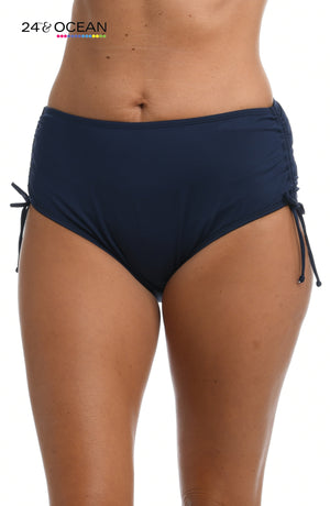 Model is wearing a solid midnight blue colored mid waist adjustable hipster bikini bottom from our 24th & Ocean brand.